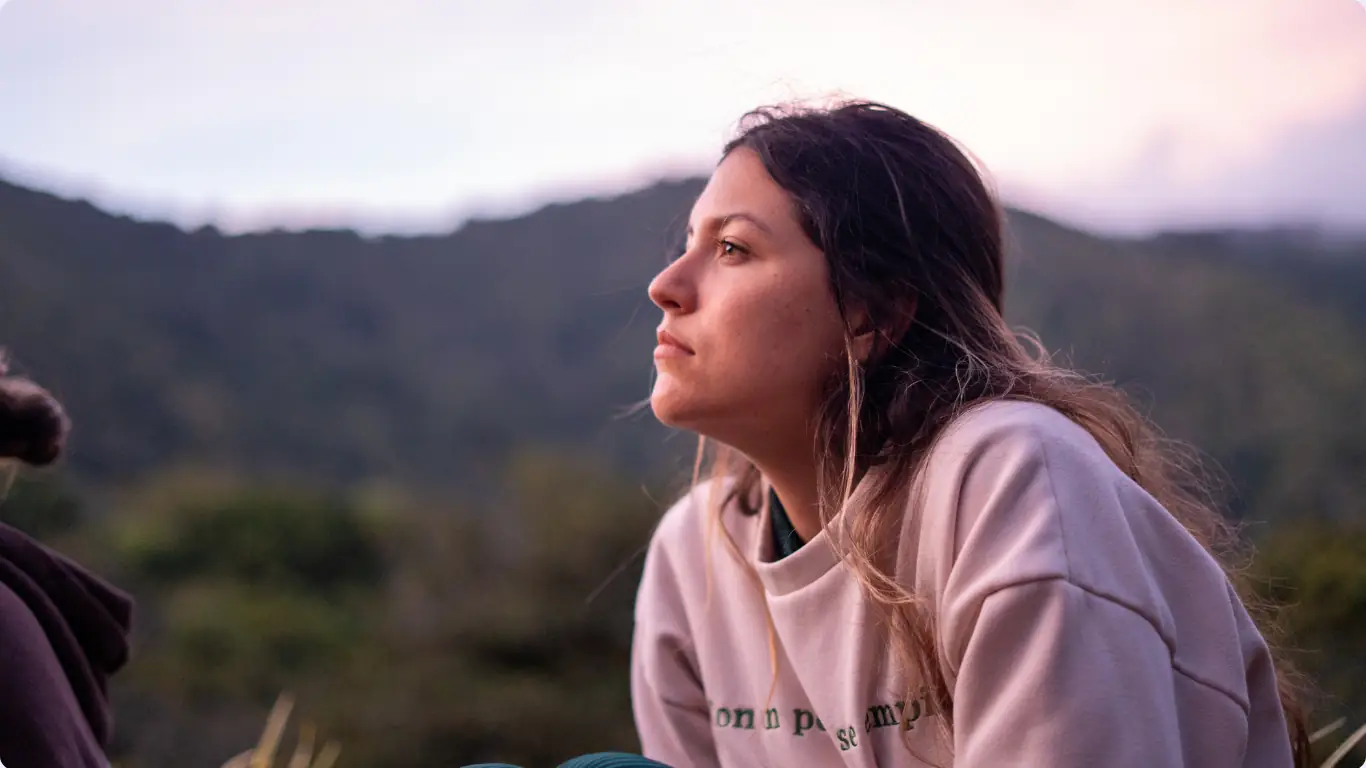 Mujer mirando hacia la montaña al atardecer, en un momento de introspección
